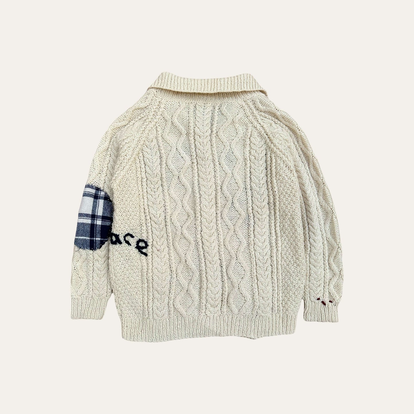 Hand-embroidered fisherman sweater with cable knit design and patchwork detail.