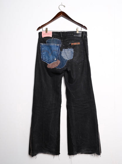 (back): Black Selvedge Patchwork Jeans – back on hanger with Lillies Studios pink label, faded black wide-leg jeans with blue and brown denim back pocket patchwork, upcycled – Lillies Studios