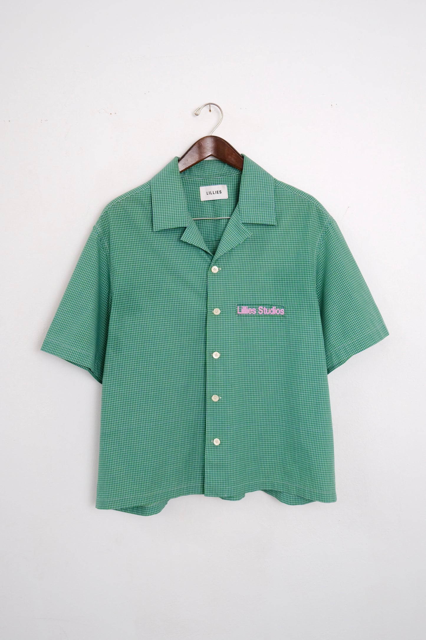 (hanger front): Cuban Collar Shirt Green – front on hanger, green micro-check camp collar shirt with Lillies Studios embroidered chest logo – Lillies Studios