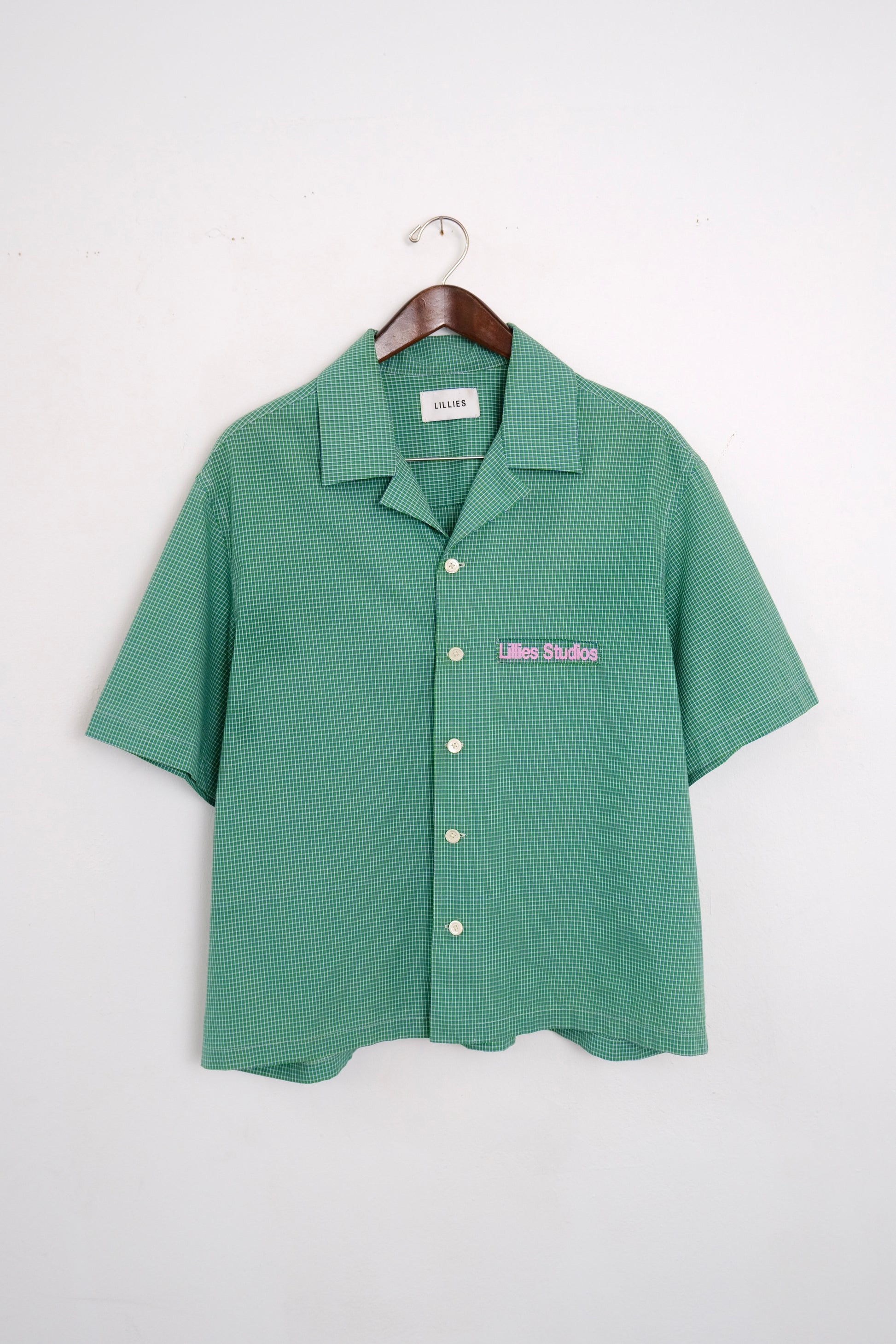 (hanger front): Cuban Collar Shirt Green – front on hanger, green micro-check camp collar shirt with Lillies Studios embroidered chest logo – Lillies Studios