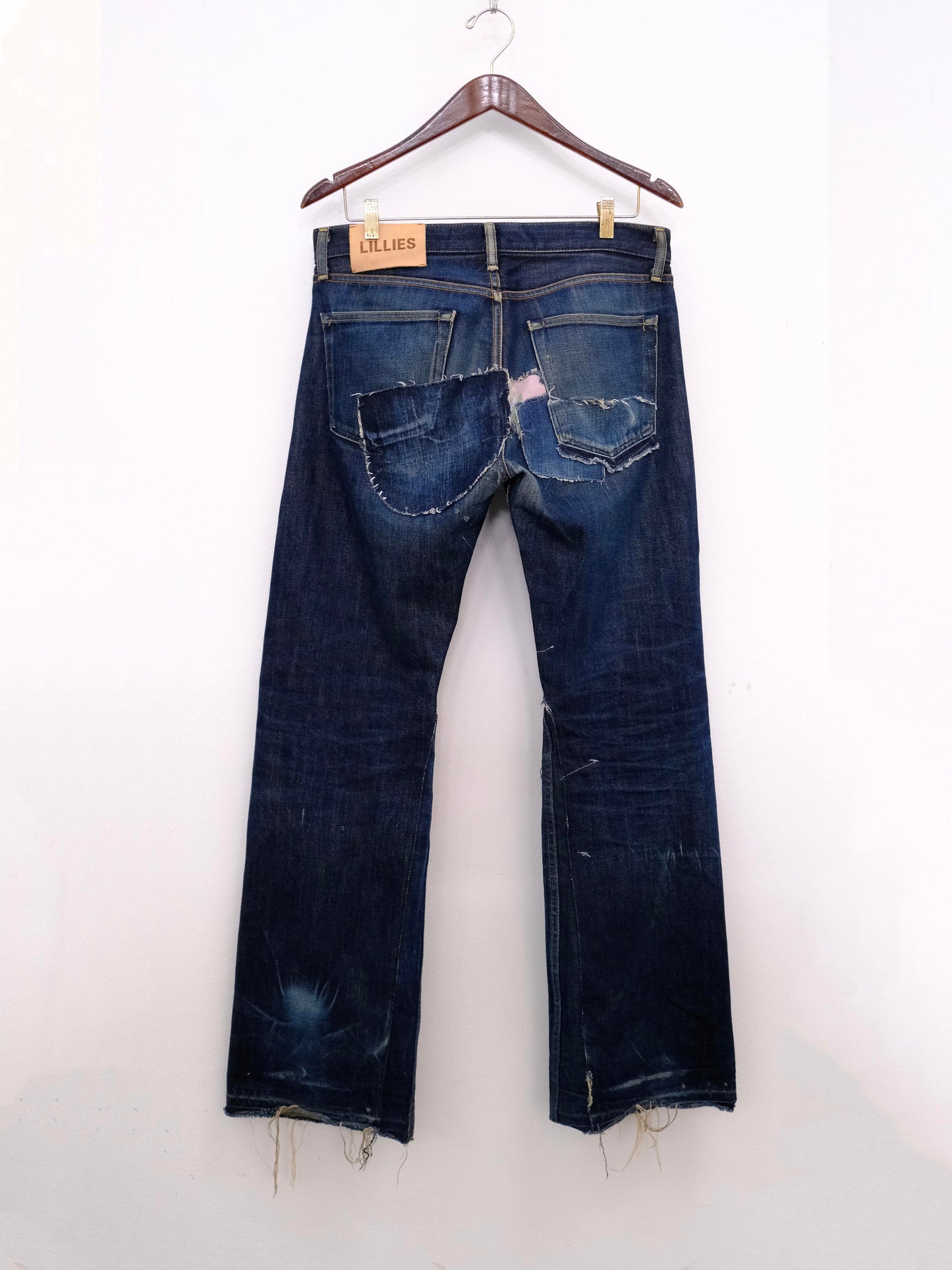 (hanger back): Japanese Selvedge Patchwork Denim – back on hanger with Lillies leather label, dark indigo selvedge jeans with patchwork back pockets, upcycled – Lillies Studios