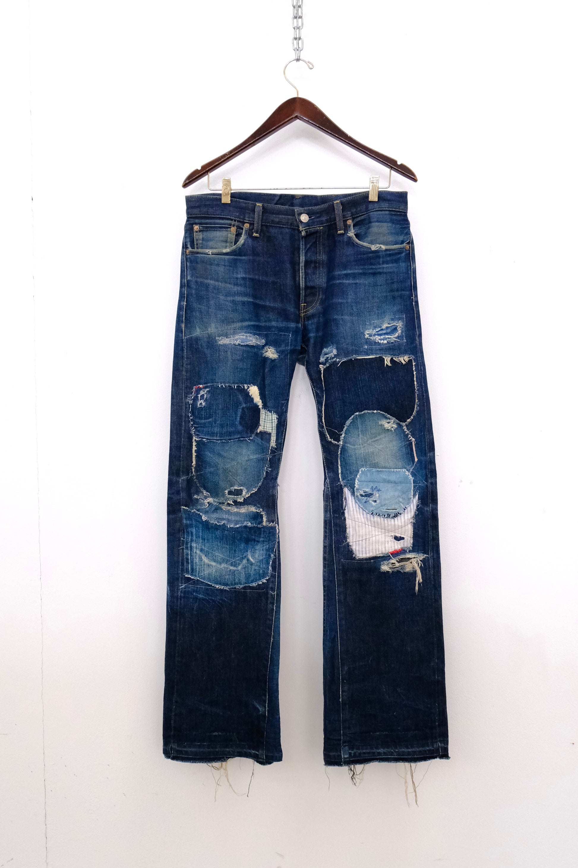 hanger front): Japanese Selvedge Patchwork Denim – front on hanger, dark indigo selvedge straight-leg jeans with heavy patchwork repairs, upcycled – Lillies Studios